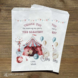 White circus theme birthday party favor bags personalized for the guest of honor.  Each is adorned with the big top tent, animals, balls and carnival fun.  Bags are larger then most and wil accomodate sweets, cookies, popcorn, peanuts.  