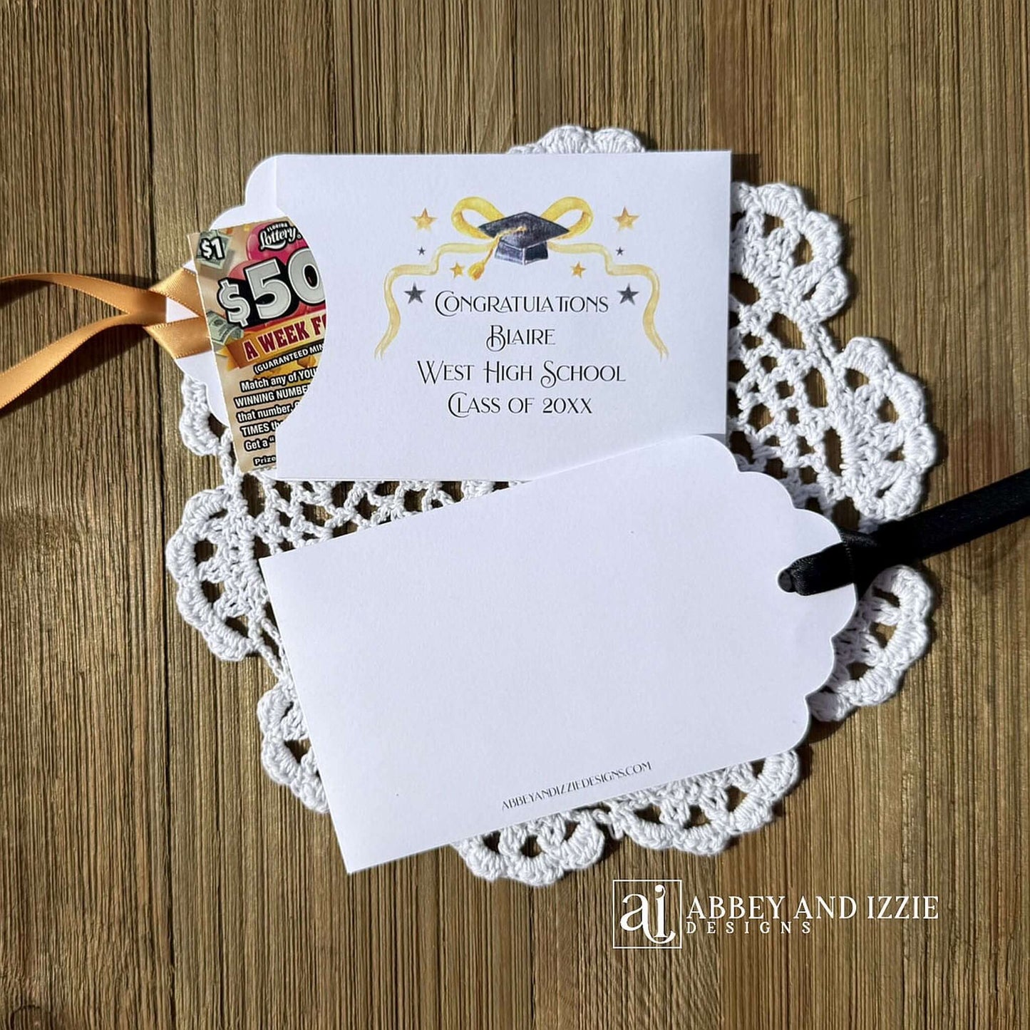 Scratch off Graduation Party Favors, printed on white card stock adorned with gold and black graduation elements.  Personalized for the guest of honor with congratulations.  Choice of black or gold ribbon which comes attahced.  Slide a lotto ticket in the open end of these envelopes for a fun party favor.