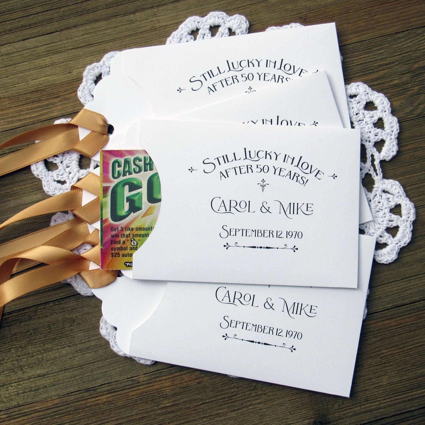Our  Lucky In Love 50th Anniversary Favors are personalized for the happy couple.  Still lucky in lover after 50 years printed on white envelopes with gold ribbon attached.  Slide a lottery ticket in the open end for a fun favor guest will love.
