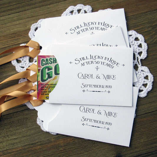 Our  Lucky In Love 50th Anniversary Favors are personalized for the happy couple.  Still lucky in lover after 50 years printed on white envelopes with gold ribbon attached.  Slide a lottery ticket in the open end for a fun favor guest will love.