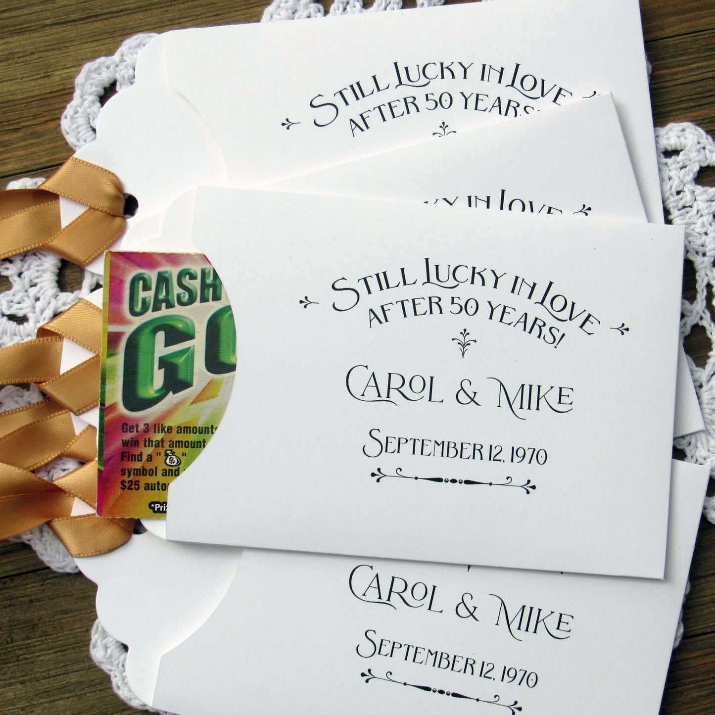 Our  Lucky In Love 50th Anniversary Favors are personalized for the happy couple.  Still lucky in lover after 50 years printed on white envelopes with gold ribbon attached.  Slide a lottery ticket in the open end for a fun favor guest will love.