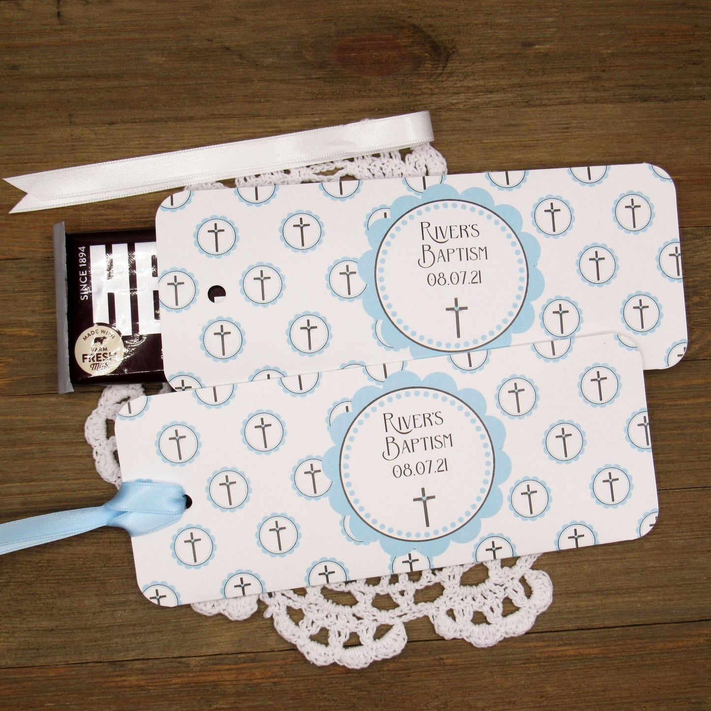 Personalized Baptism Party Favors for Baby Boys.  Printed on white card stock adorned with blue crosses with babies name and baptism date.  Choice of light blue or white ribbon which is included and left off for easy filling.  Slide a candy bar in the open end and tie the ribbon.