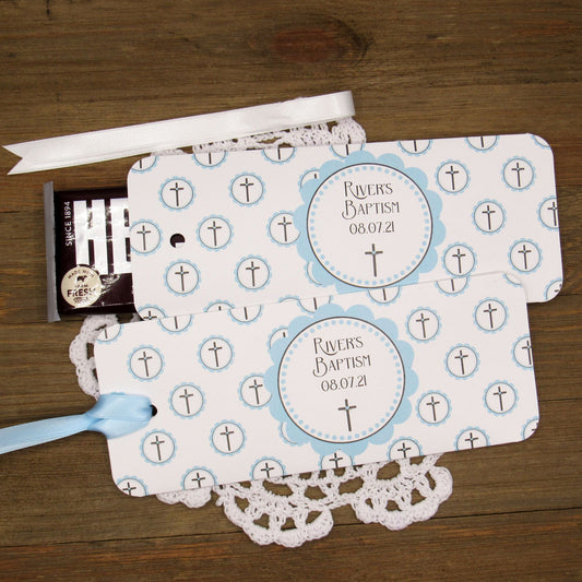 Personalized Baptism Party Favors for Baby Boys.  Printed on white card stock adorned with blue crosses with babies name and baptism date.  Choice of light blue or white ribbon which is included and left off for easy filling.  Slide a candy bar in the open end and tie the ribbon.