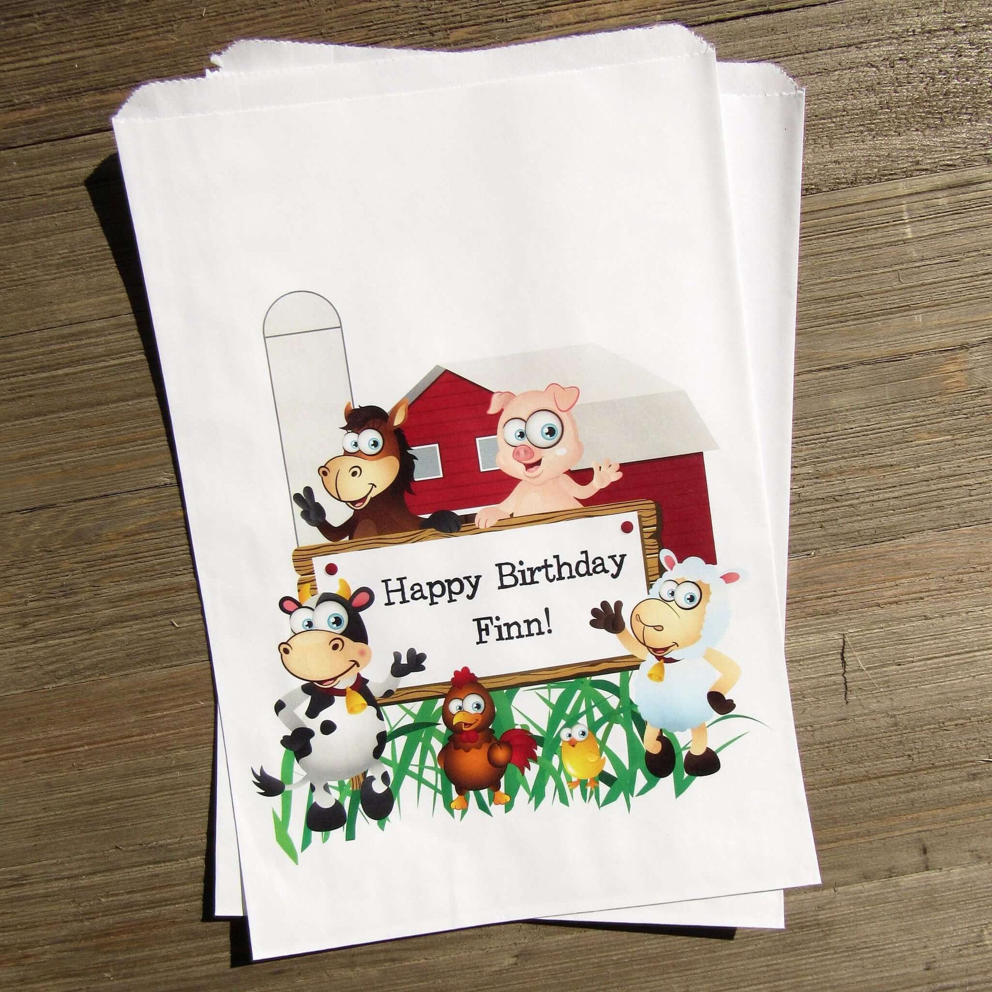 Farm Theme Birthday Party Goodie Bags personalized for the guest of honor.  Printed on white bags, adorned with cute farm animals.  Fill these goodie bags with candy, cookies, popcorn or fun favors.
