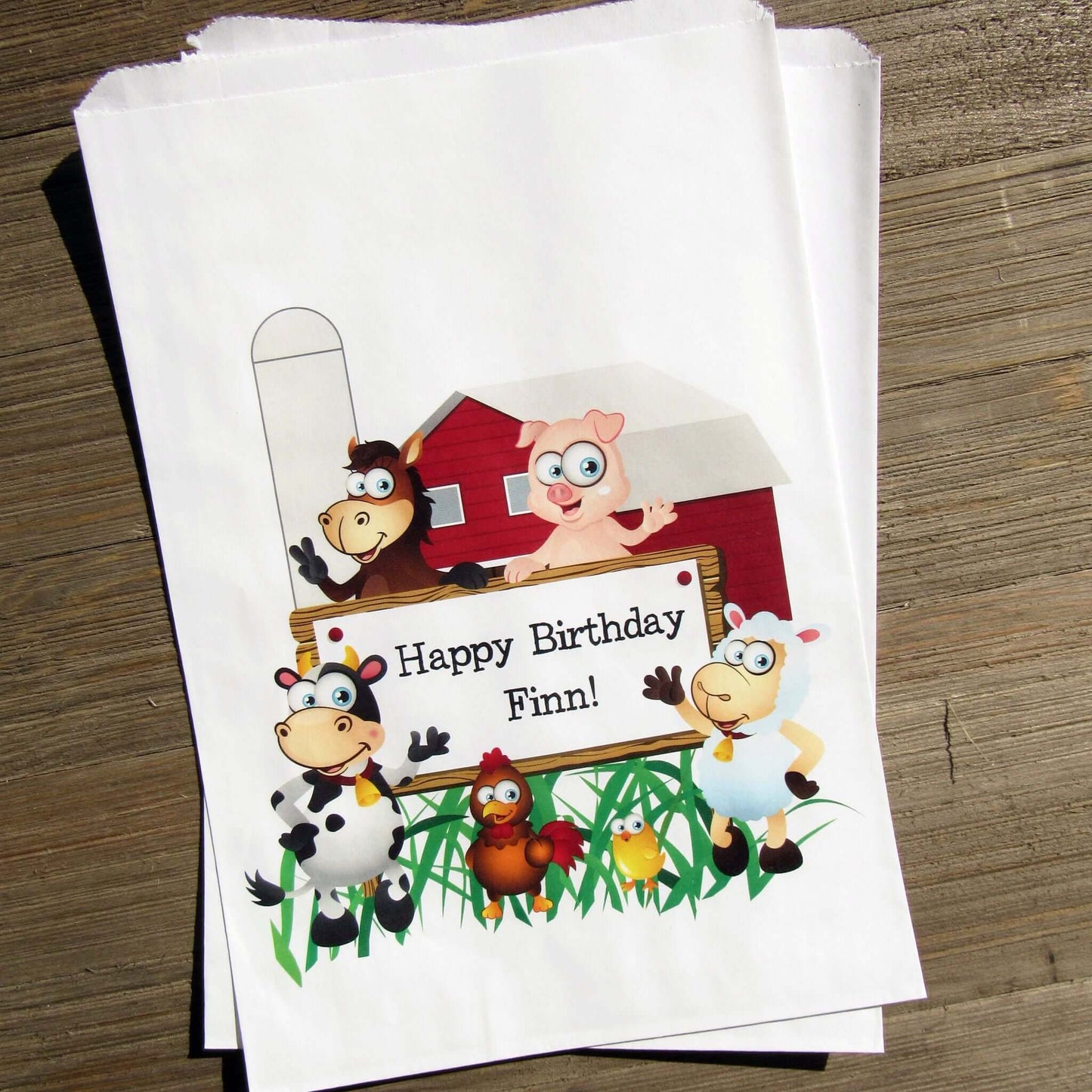 Farm Theme Birthday Party Goodie Bags personalized for the guest of honor.  Printed on white bags, adorned with cute farm animals.  Fill these goodie bags with candy, cookies, popcorn or fun favors.