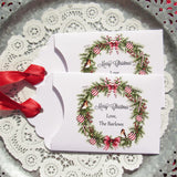 Personalized Christmas Party Favors adorned with a beautiful wreath and a red ribbon attached.  These can be used for lottery ticket favors or gift card holders.