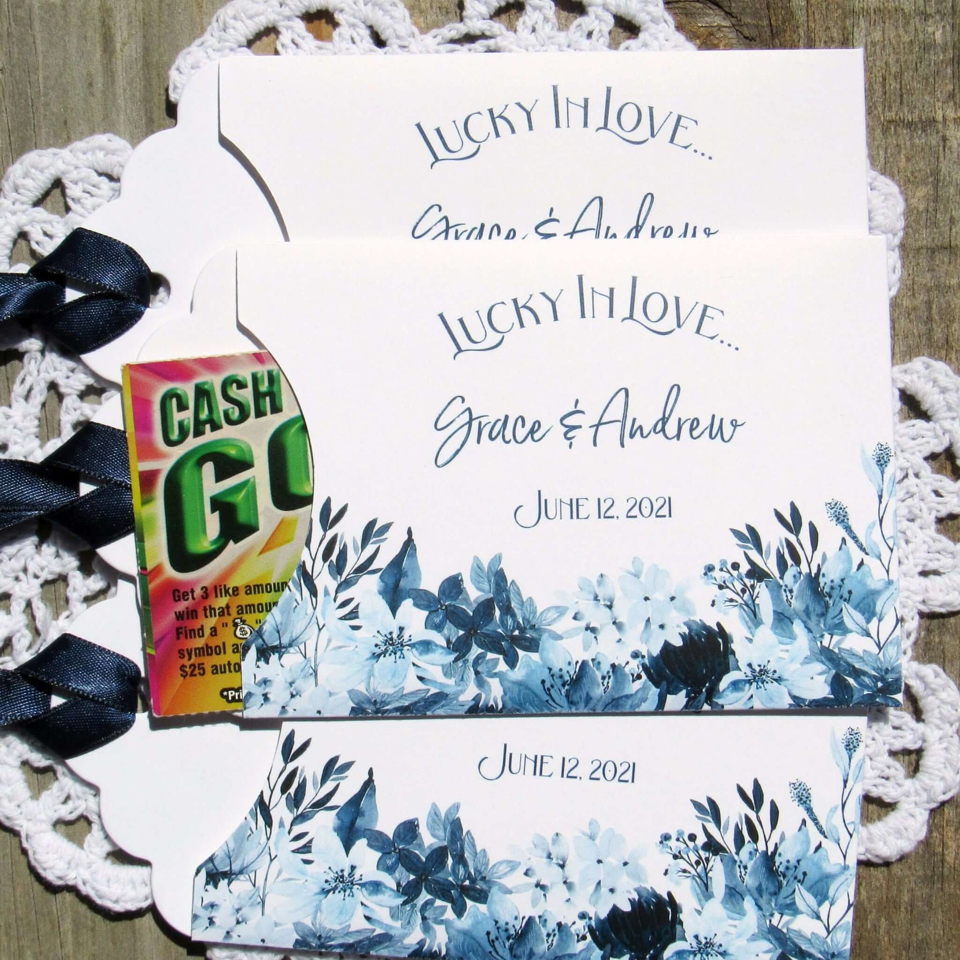 Navy Blue Wedding Guest Favors, slide a lotto ticket in to see who wins.  Envelopes are printed on white card stock adorned with blue flowers and a navy blue ribbon comes attached.  Lucky In Love printed with the bride and grooms names below.  