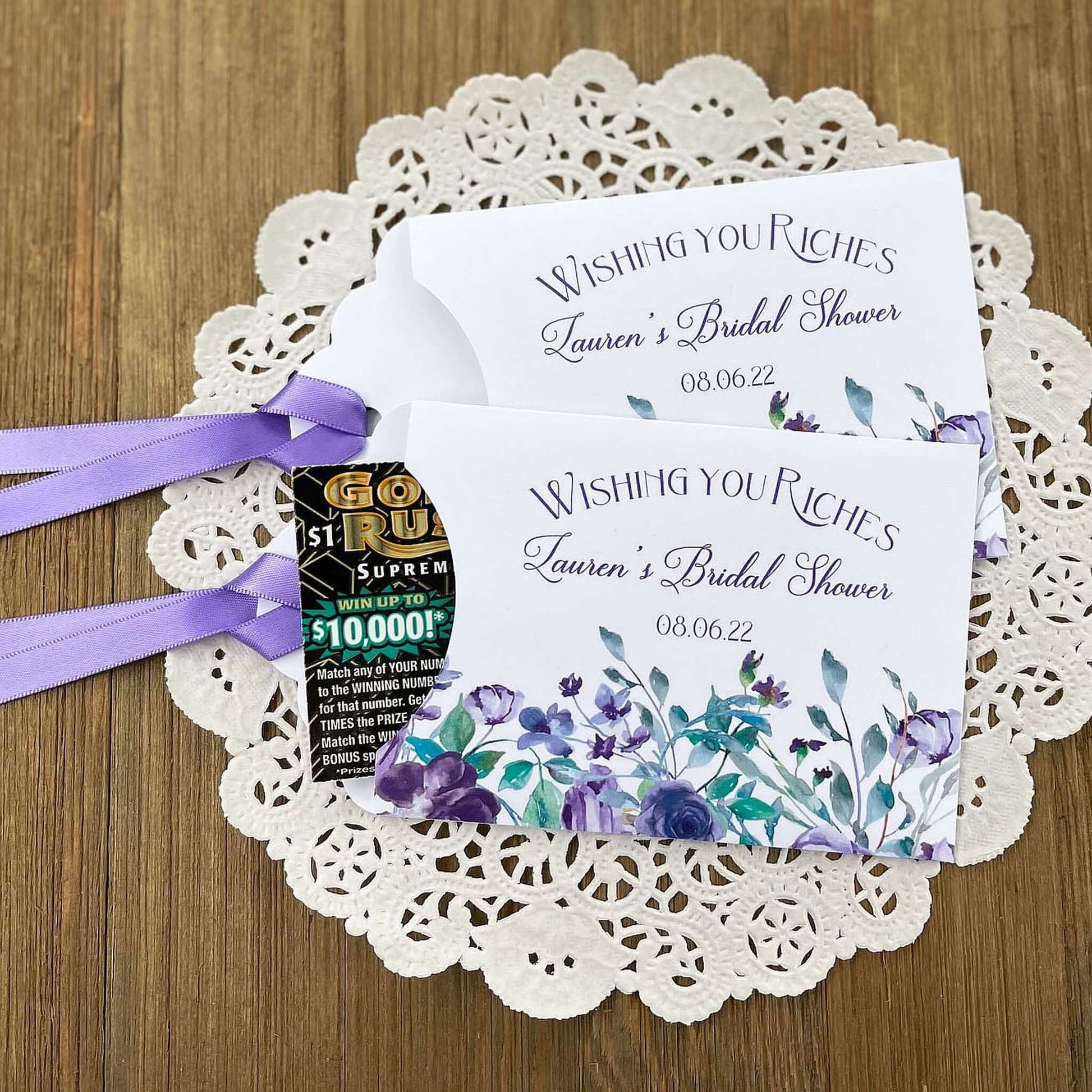 Wishing You Riches Lavender Bridal Shower Lottery Favors are personalized for the bride to be.  Lotto ticket envelopes adorned with lavender flowers and ribbon, slide a lottery ticket in to see who wins big with these fun shower favors.