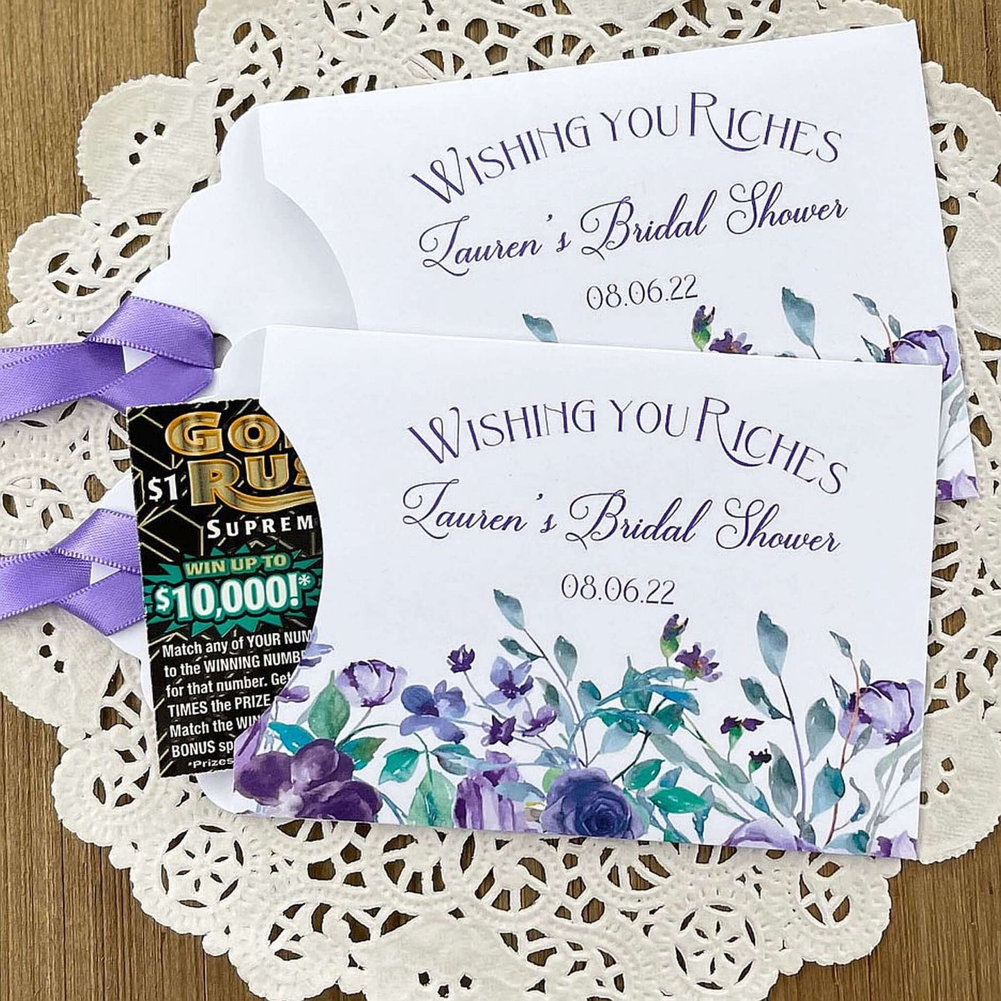 Wishing You Riches Lavender Bridal Shower Lottery Favors are personalized for the bride to be.  Lotto ticket envelopes adorned with lavender flowers and ribbon, slide a lottery ticket in to see who wins big with these fun shower favors.