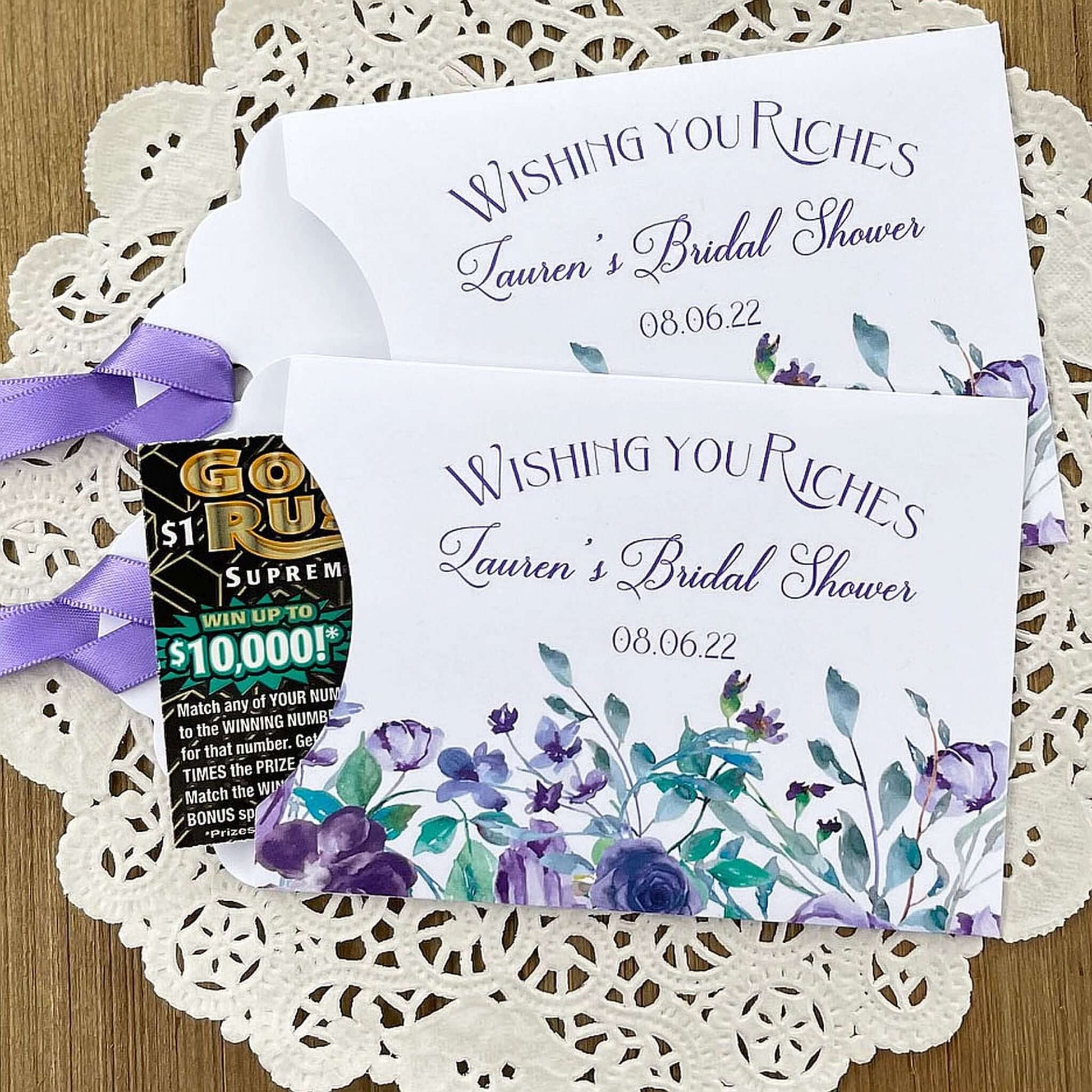 Wishing You Riches Lavender Bridal Shower Lottery Favors are personalized for the bride to be.  Lotto ticket envelopes adorned with lavender flowers and ribbon, slide a lottery ticket in to see who wins big with these fun shower favors.