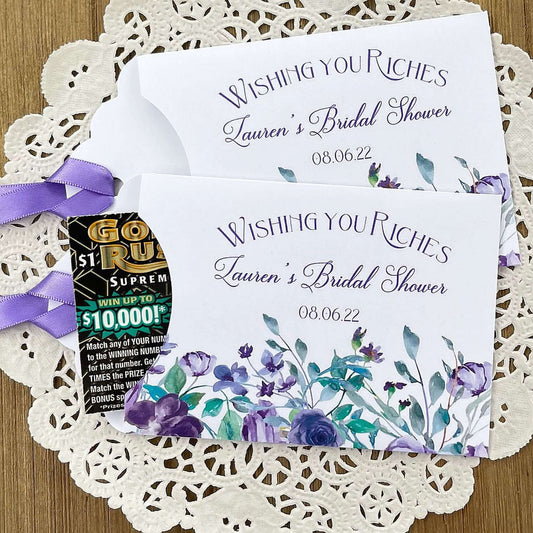 Wishing You Riches Lavender Bridal Shower Lottery Favors are personalized for the bride to be.  Lotto ticket envelopes adorned with lavender flowers and ribbon, slide a lottery ticket in to see who wins big with these fun shower favors.