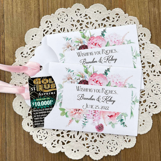 Pink Floral Wedding Favors Personalized  personalized for the bride and groom.  White lottery ticket favors adorned with pink floral with a pink ribbon attached.  Slide a scratch off ticket in for a fun wedding guest favor.